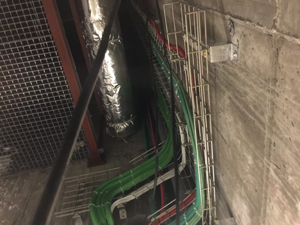 Bandejas de rejilla metálica con cables de fuerza en pared de hormigón en Potencia y Control